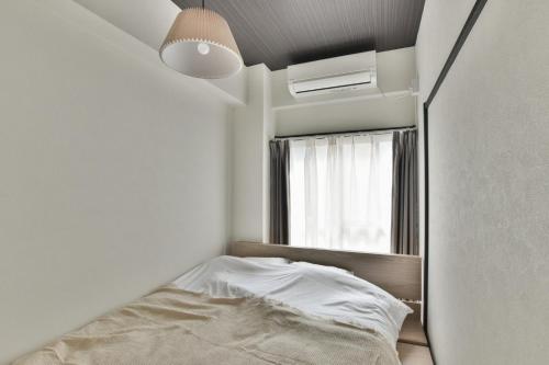 Habitación pequeña con cama y ventana en 岡田ビル5階, en Tokio