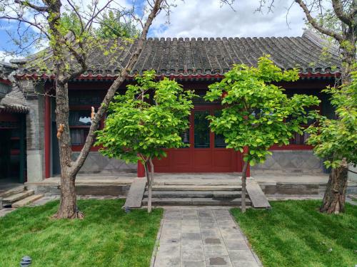 ein Haus mit einer roten Tür und zwei Bäumen in der Unterkunft Beijing Heyuan Courtyard Hotel (Forbidden City) in Peking