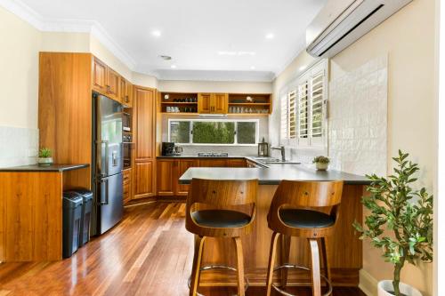a kitchen with wooden cabinets and a island with bar stools at Roselawn Manor - 5 Bedroom Entertainer in Orange