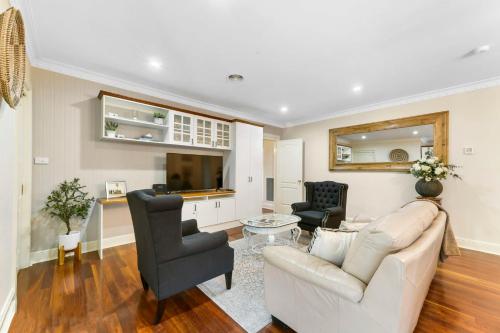 a living room with a white couch and a tv at Roselawn Manor - 5 Bedroom Entertainer in Orange