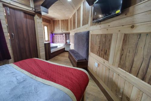 Zimmer mit einem Bett und einem TV an einer Holzwand in der Unterkunft Goroomgo Payal Lake View Mall Road Nainital in Nainital
