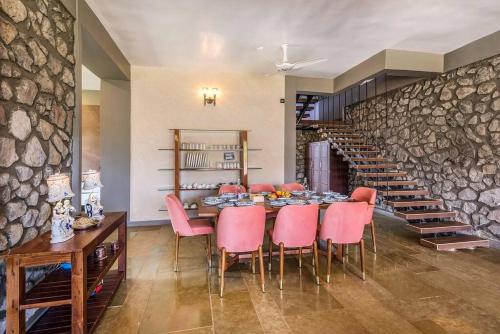 a dining room with a table and pink chairs at STONE Mansion by Phoenix Stays Igatpuri in Igatpuri