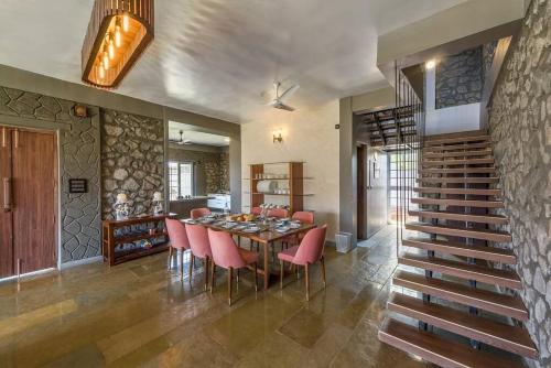a dining room with a table and pink chairs at STONE Mansion by Phoenix Stays Igatpuri in Igatpuri