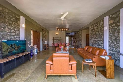 a living room with couches and a flat screen tv at STONE Mansion by Phoenix Stays Igatpuri in Igatpuri