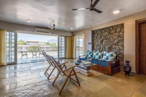 a living room with a blue couch and a stone wall at STONE Mansion by Phoenix Stays Igatpuri in Igatpuri