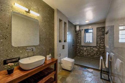 a bathroom with a sink and a toilet and a shower at STONE Mansion by Phoenix Stays Igatpuri in Igatpuri