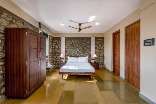 a bedroom with a bed and a stone wall at STONE Mansion by Phoenix Stays Igatpuri in Igatpuri