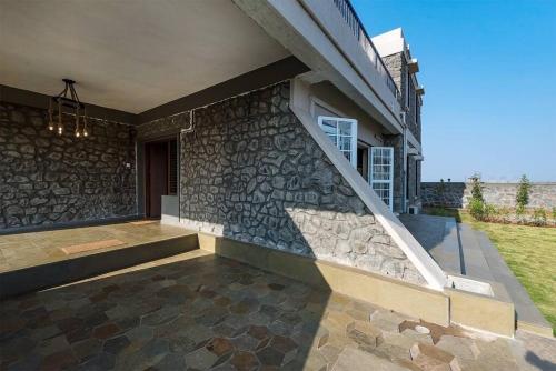 a house with a stone wall and a staircase at STONE Mansion by Phoenix Stays Igatpuri in Igatpuri