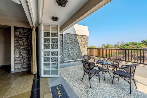 a patio with a table and chairs on a balcony at STONE Mansion by Phoenix Stays Igatpuri in Igatpuri