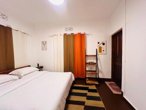 sypialnia z białym łóżkiem i pomarańczowymi zasłonami w obiekcie Makini Spaces w mieście Arusza