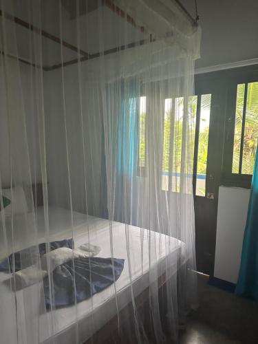 a bedroom with a bed with white mosquito netting at Ayur Nelum Villa in Bentota