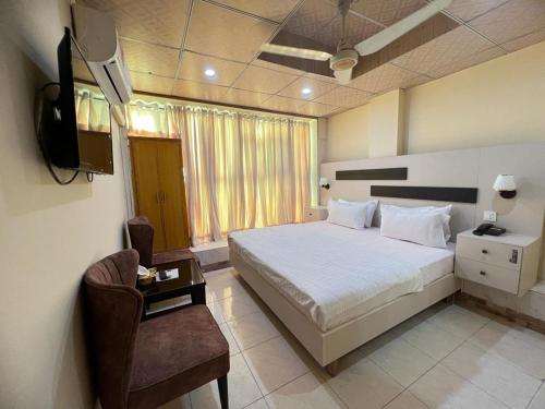 Schlafzimmer mit einem Bett, einem TV und einem Stuhl in der Unterkunft Islamabad Premium Hotel in Islamabad
