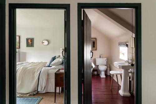 a bedroom with a bed and a bathroom with a sink at Stour Valley Cottage in Wimborne Minster