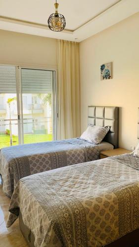 two beds in a bedroom with a large window at Residence Casa Bay Sidi Rahal in Sidi Rahal