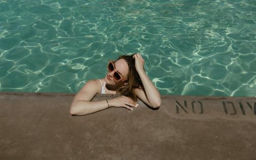 a woman in a swimming pool with a no dip sign at Balcomo, a Ramada by Wyndham in Penticton
