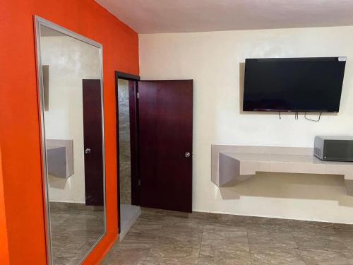 Habitación con TV de pantalla plana en la pared en hotel roger Inn mazatlan, en Mazatlán