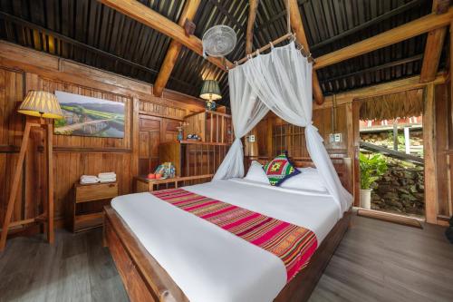 a bedroom with a bed with a mosquito net at Gateway Inn Puluong in Pu Luong