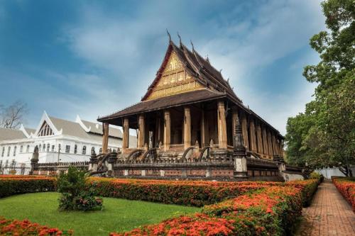 um pagode num jardim em frente a um edifício em TT Premium Hostel Vientiane em Vientiane