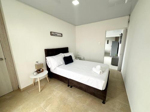 ein kleines Schlafzimmer mit einem Bett und einem Tisch in der Unterkunft Cómodo Apartamento Cerca Al Aeropuerto in Pereira