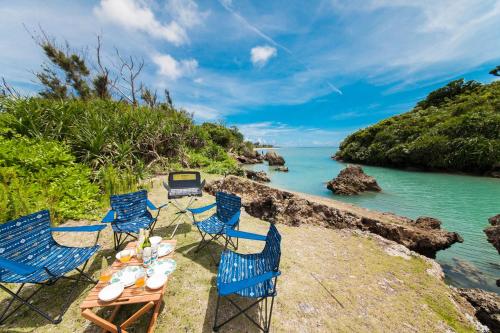 a group of blue chairs and a table on a beach at ガジュマルの庭～itoman in Ō