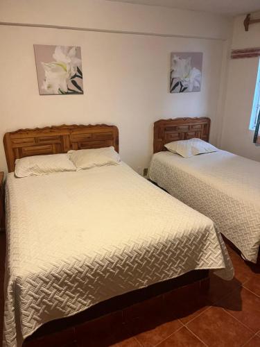 a bedroom with two beds and two paintings on the wall at Hotel La Loma in Huasca de Ocampo