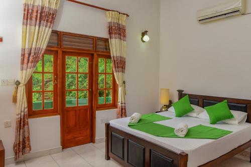 1 dormitorio con 1 cama grande con almohadas verdes en Siyonra Bungalow, en Matale