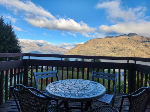 a table and chairs on a balcony with mountains at Devine Hideaway - Family Rustic Kiwi Bach - Beautiful Lake Views in Queenstown
