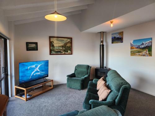 a living room with two couches and a flat screen tv at Devine Hideaway - Family Rustic Kiwi Bach - Beautiful Lake Views in Queenstown