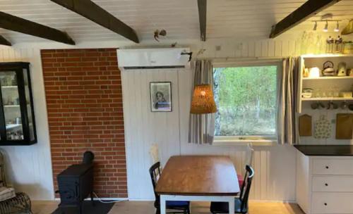 uma cozinha com uma mesa e uma parede de tijolos em Cozy Cottage Nearby Great Sandy Beach em Højby