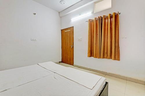 a room with a bed and a wooden door at OYO Hotel Surya Palace in Kushinagar