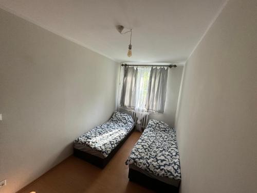 Duas camas num pequeno quarto com uma janela em Witawa 2024 em Gdynia