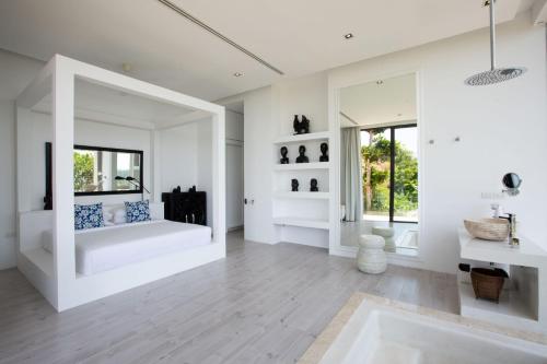 una sala de estar con paredes blancas y un espejo grande. en Villa Belle, en Choeng Mon Beach