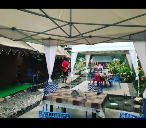 un patio con tavolo e sedie sotto una tenda. di Parvati Camp's Kasol a Kasol