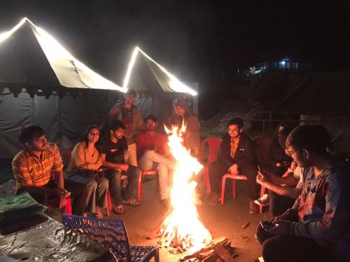 Un groupe de gens assis autour d'un feu dans l'établissement Parvati Camp's Kasol, à Kasol