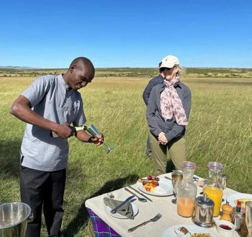 a man and a woman standing next to a table with food at Wildlife Enthusiasts in Sekenani