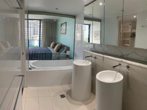 y baño con 2 lavabos, bañera y espejo. en Oracle resort apartment, en Gold Coast