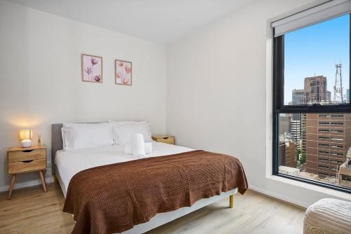 a white bedroom with a bed and a large window at Luxe Lonsdale - Your City Retreat in Melbourne in Melbourne