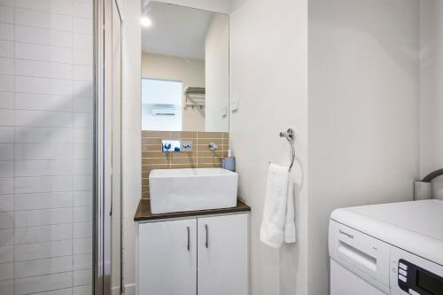 a white bathroom with a sink and a mirror at Luxe Lonsdale - Your City Retreat in Melbourne in Melbourne