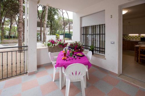 a table with a pink table cloth on a balcony at Villa Margherita in Rosolina Mare