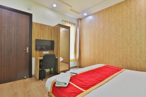 een slaapkamer met een bed, een bureau en een televisie bij Hotel Aarya in Lucknow