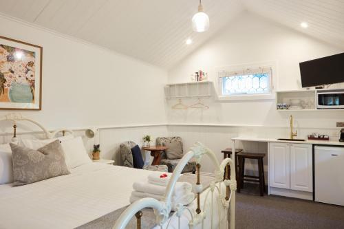 a white bedroom with a bed and a kitchen at Tiffany's Cottages in Bright