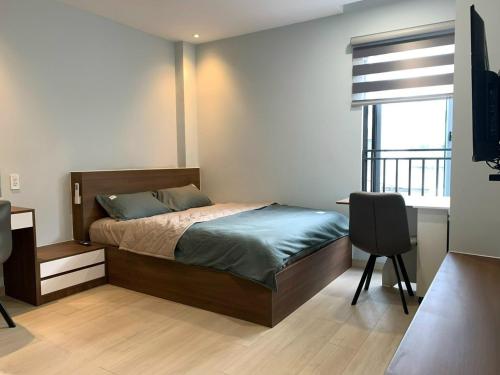 Schlafzimmer mit einem Bett, einem Schreibtisch und einem Fenster in der Unterkunft LUCY HOTEL & APARTMENT D1 in Ho-Chi-Minh-Stadt