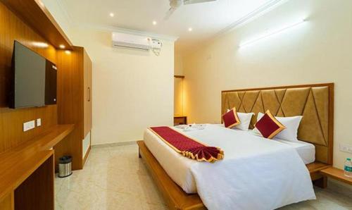 a bedroom with a large bed and a flat screen tv at FabHotel Prime AR Phalazzo Resort in Puducherry