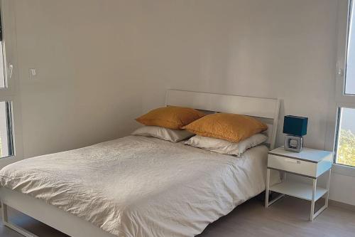 een bed met 2 kussens en een nachtkastje naast een raam bij Maison neuf centre ville in Metz