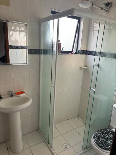 Un baño con ducha de cristal y lavabo. en Apartamento beira-mar em Mongaguá, en Mongaguá
