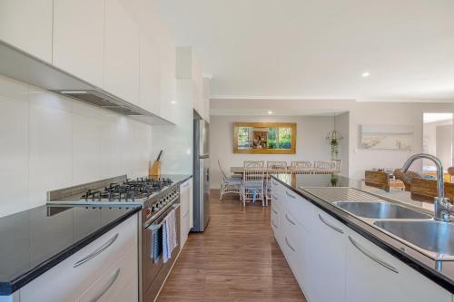 a kitchen with a sink and a stove top oven at Contemporary Home in the Heart of Mudjimba in Mudjimba