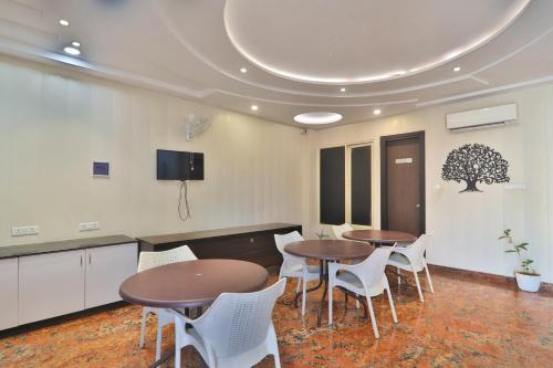 une salle de réunion avec deux tables et des chaises blanches dans l'établissement Hotel Aarya, à Lucknow