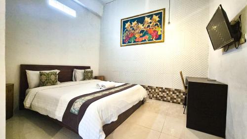 a bedroom with a bed and a painting on the wall at The Paica in Denpasar