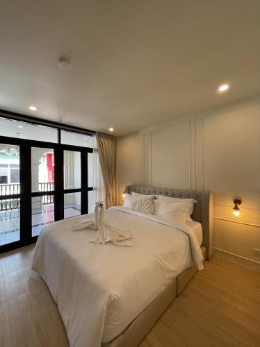 een slaapkamer met een groot bed met witte lakens bij Hawa House Phuket in Phuket