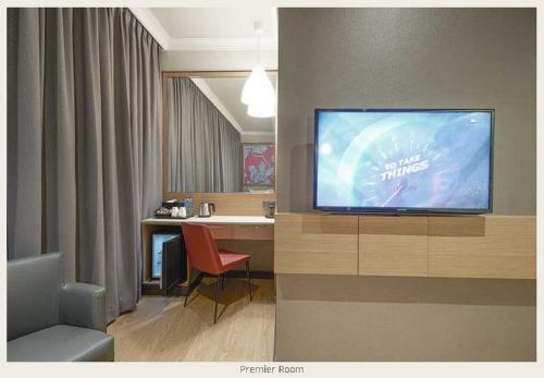 a room with a television and a desk with a chair at Hotel Bencoolen at Hong Kong Street in Singapore
